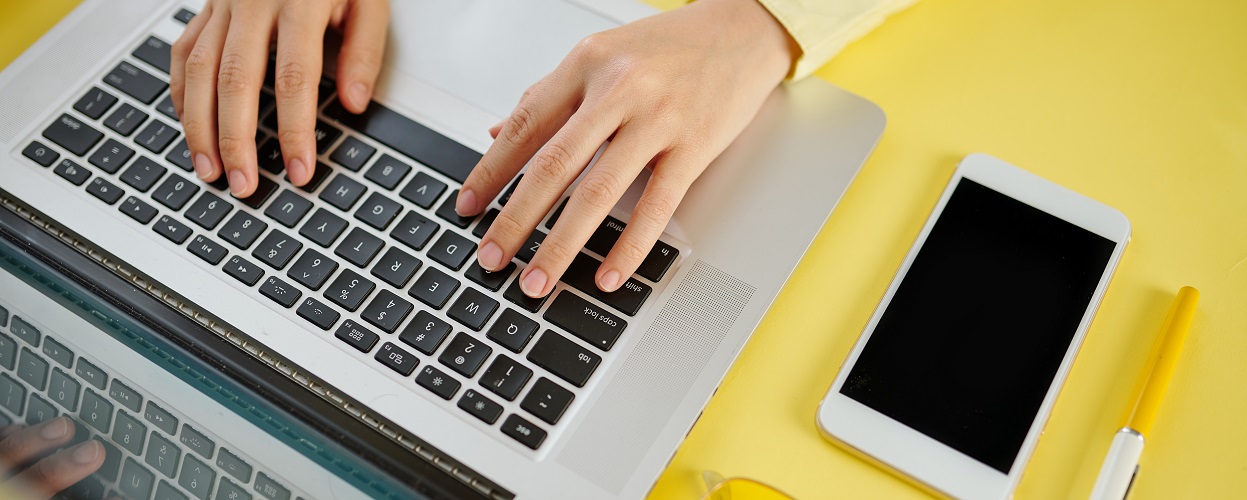 Mãos de uma mulher trabalhando em um notebook no seu escritório